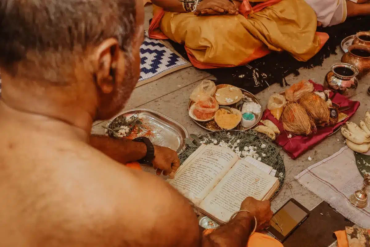 गीता के 18 अध्याय का सार: हर अध्याय का नाम, श्लोक संख्या, मुख्य श्लोक और आज की सीख पूजा की थाली के पास बैठकर पोथी का पाठ करते व्यक्ति