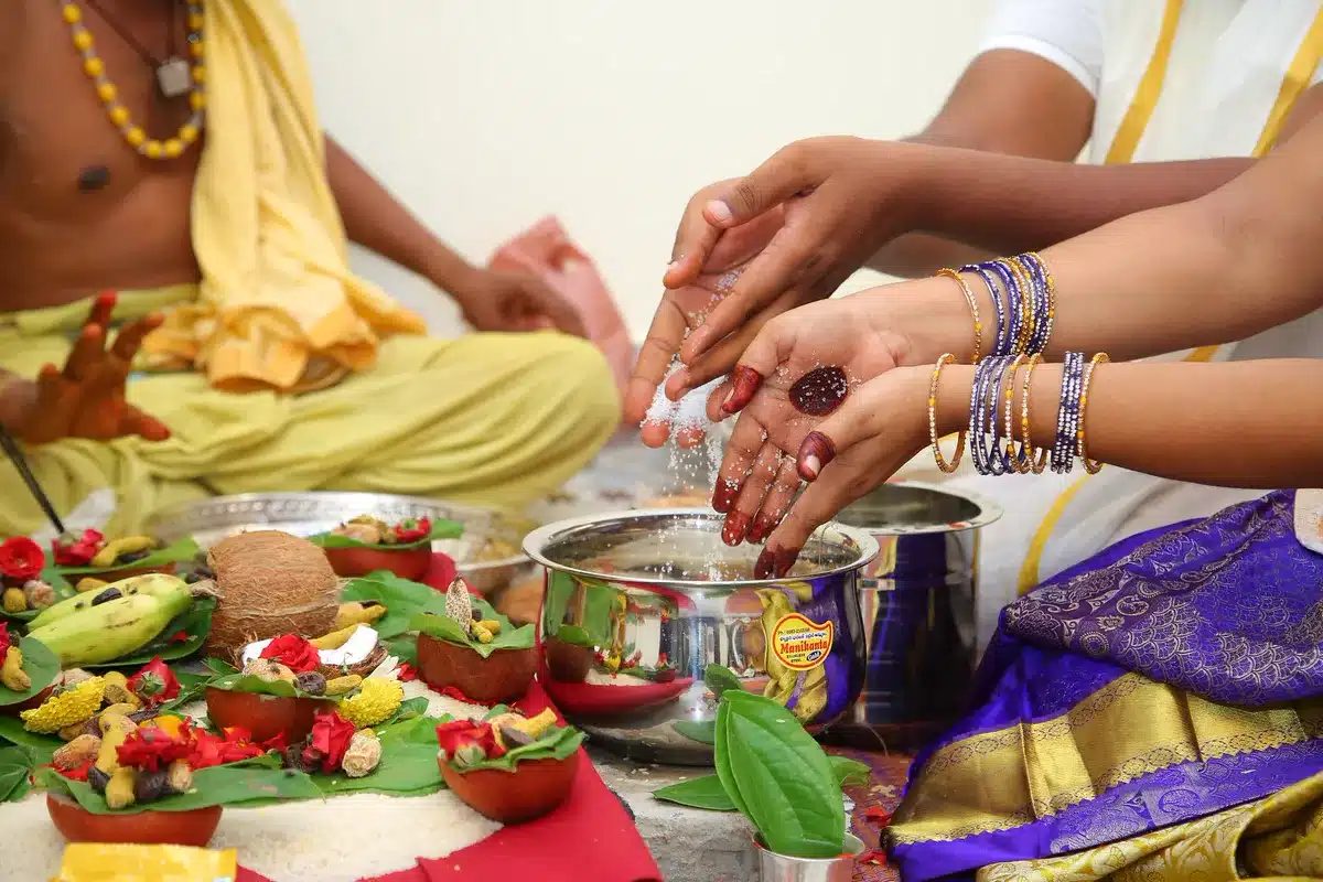 सत्यनारायण व्रत कथा: पाँचों अध्याय, पूजा विधि और प्रसाद पूजा में प्रसाद और फूल अर्पित करते हाथ